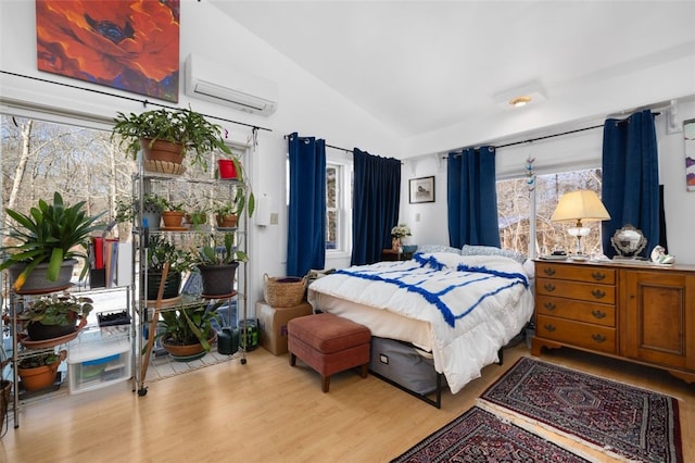 bedroom featuring lofted ceiling, a wall mounted AC, and light hardwood / wood-style floors