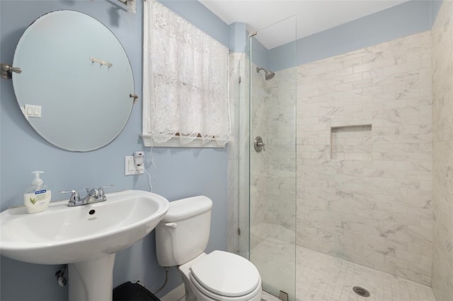 bathroom featuring a tile shower, sink, and toilet