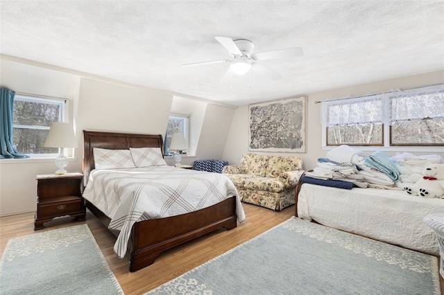 bedroom featuring multiple windows, hardwood / wood-style flooring, a textured ceiling, and ceiling fan