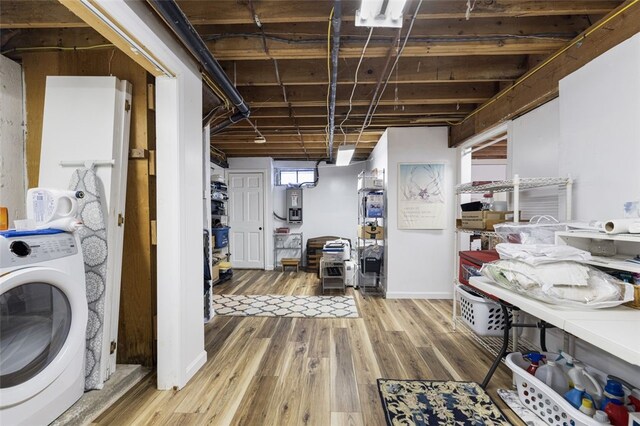 clothes washing area with washer / clothes dryer and light wood-type flooring