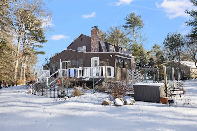 snow covered property with a hot tub and a deck