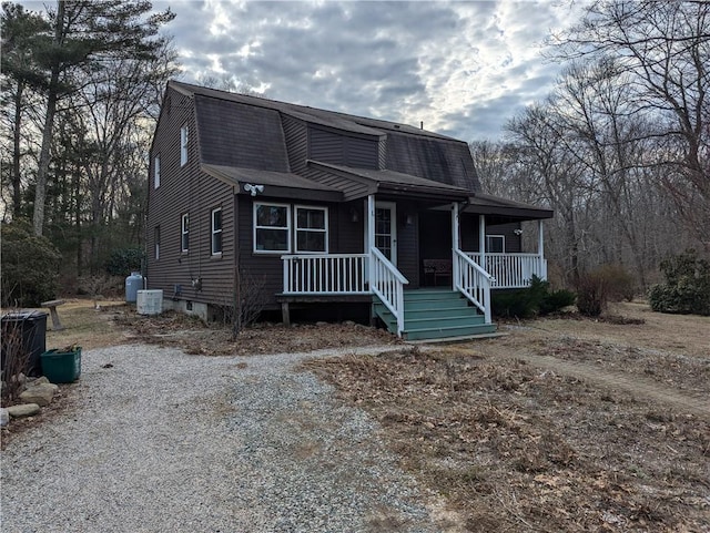 colonial inspired home featuring a gambrel roof, roof with shingles, and a porch