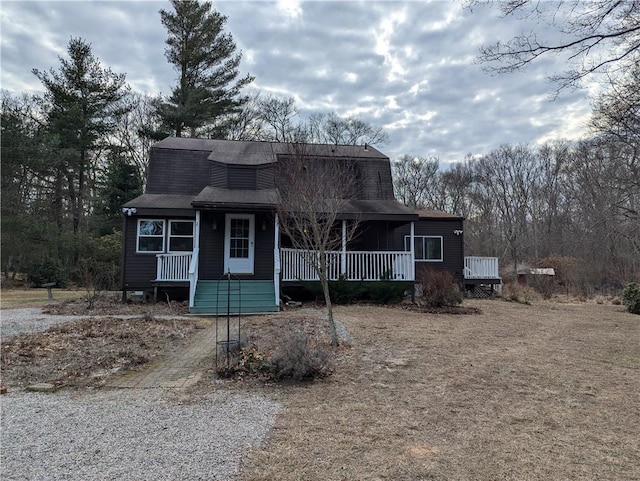 colonial inspired home featuring a porch, a gambrel roof, and roof with shingles