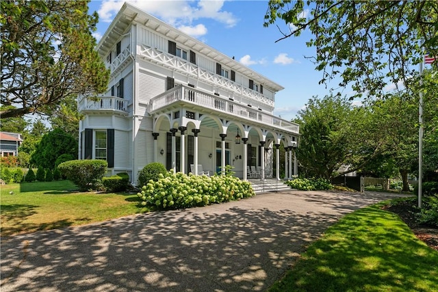 exterior space featuring a front lawn, a balcony, and covered porch