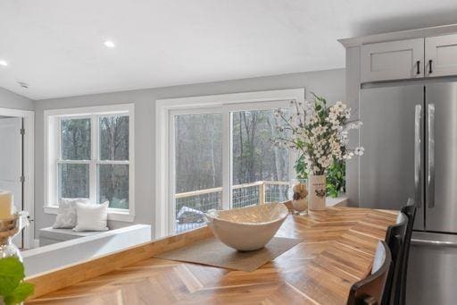 dining space featuring parquet flooring, plenty of natural light, and vaulted ceiling