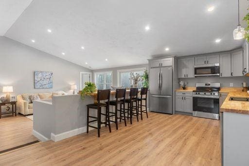 kitchen featuring gray cabinetry, decorative light fixtures, light wood-type flooring, and appliances with stainless steel finishes