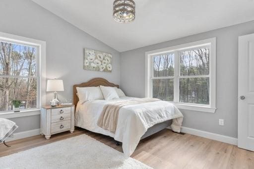 bedroom with multiple windows, wood-type flooring, and lofted ceiling