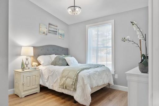 bedroom with vaulted ceiling, a notable chandelier, and light hardwood / wood-style flooring