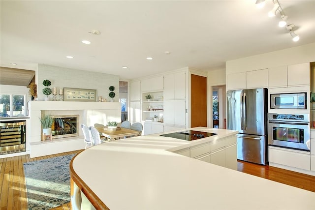 kitchen with stainless steel appliances, beverage cooler, dark hardwood / wood-style flooring, and white cabinets