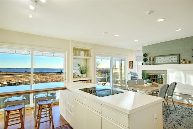 kitchen with black electric cooktop, dark hardwood / wood-style floors, a kitchen island, and white cabinets