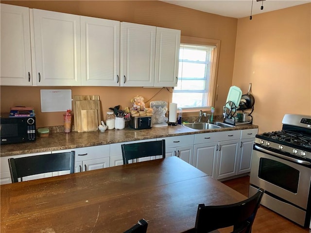 kitchen with stainless steel range with gas cooktop, sink, dark wood-type flooring, and white cabinets