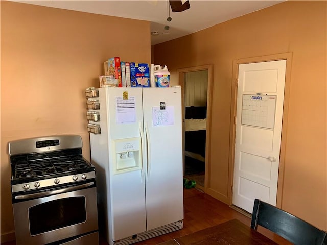 kitchen with dark wood-type flooring, ceiling fan, stainless steel range with gas stovetop, and white refrigerator with ice dispenser