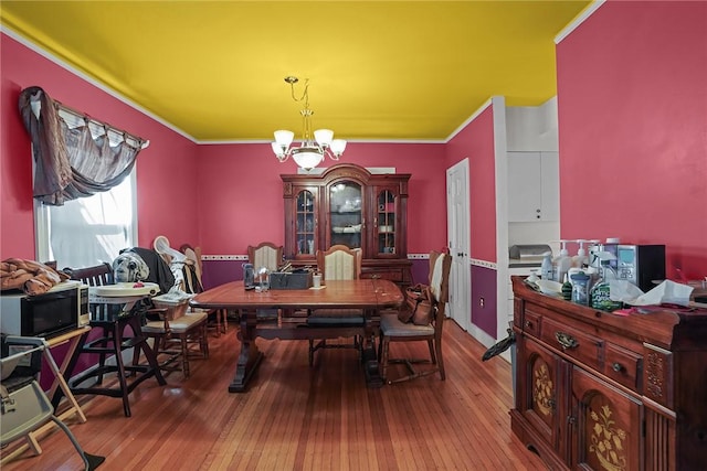 dining area featuring hardwood / wood-style flooring, ornamental molding, and a chandelier