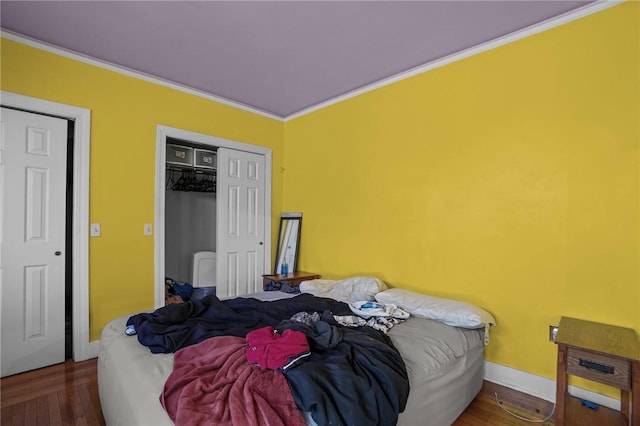 bedroom featuring dark wood-type flooring, ornamental molding, and a closet