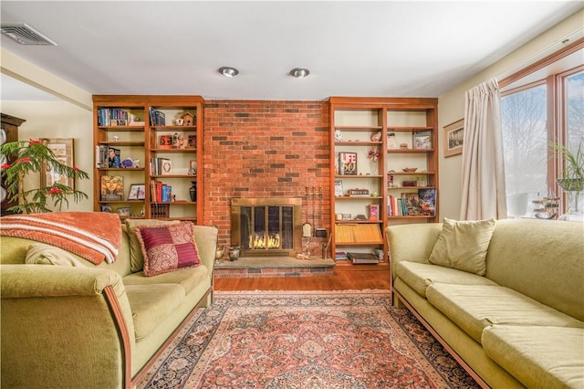 living room with wood-type flooring and a brick fireplace