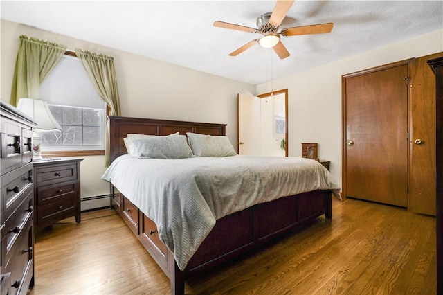 bedroom with a baseboard radiator, hardwood / wood-style floors, and ceiling fan