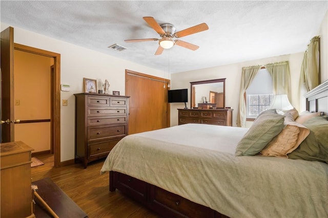 bedroom with a closet, a textured ceiling, dark hardwood / wood-style floors, and ceiling fan