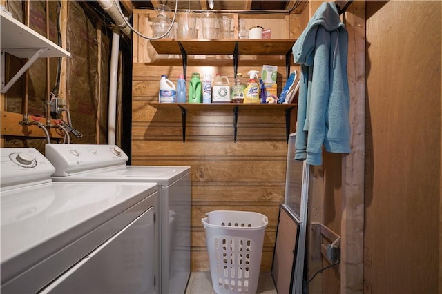 washroom with washing machine and clothes dryer and wood walls