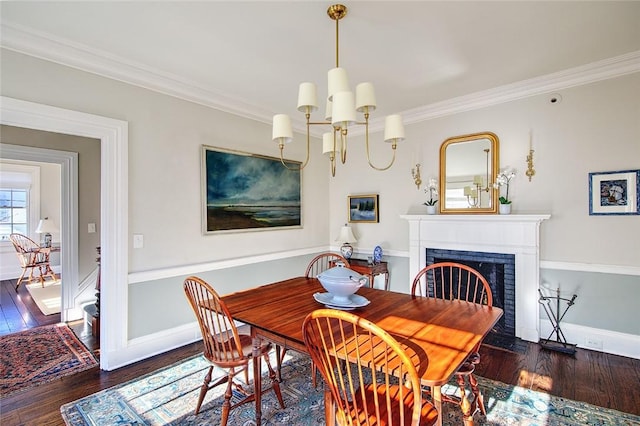 dining space featuring dark hardwood / wood-style flooring, a notable chandelier, crown molding, and a fireplace