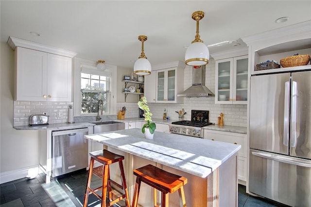 kitchen featuring appliances with stainless steel finishes, sink, white cabinets, a center island, and wall chimney exhaust hood