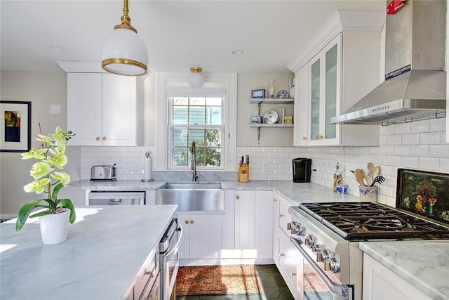 kitchen with decorative light fixtures, tasteful backsplash, white cabinetry, stainless steel appliances, and wall chimney exhaust hood