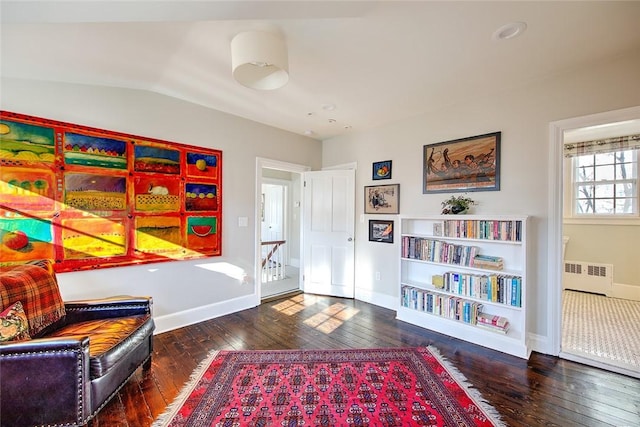 living area featuring dark wood-type flooring, radiator, and vaulted ceiling