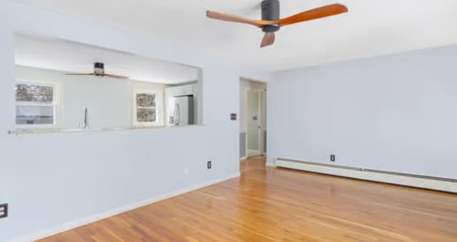 unfurnished room featuring baseboard heating, ceiling fan, and hardwood / wood-style floors