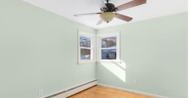 unfurnished room featuring a baseboard heating unit, light hardwood / wood-style flooring, and ceiling fan