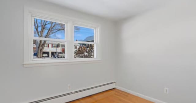 unfurnished room featuring wood-type flooring and baseboard heating