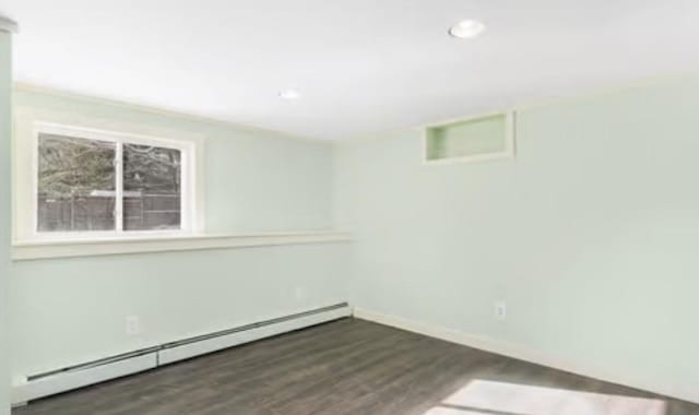 spare room with baseboard heating and dark hardwood / wood-style flooring