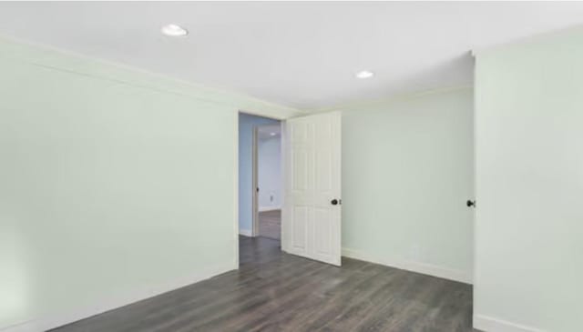 unfurnished room featuring dark wood-type flooring and ornamental molding