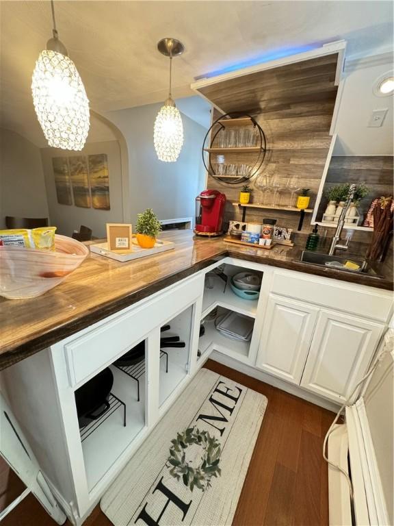 interior space with wooden walls, butcher block countertops, decorative light fixtures, white cabinets, and dark hardwood / wood-style flooring