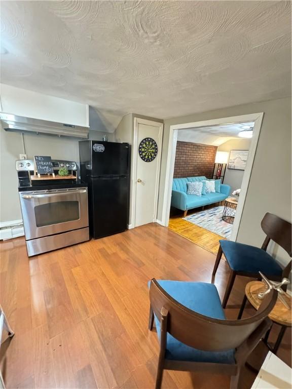 kitchen featuring electric stove, black fridge, light hardwood / wood-style floors, and a textured ceiling