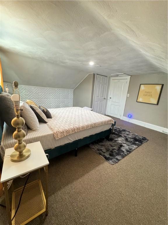 carpeted bedroom featuring lofted ceiling and a textured ceiling