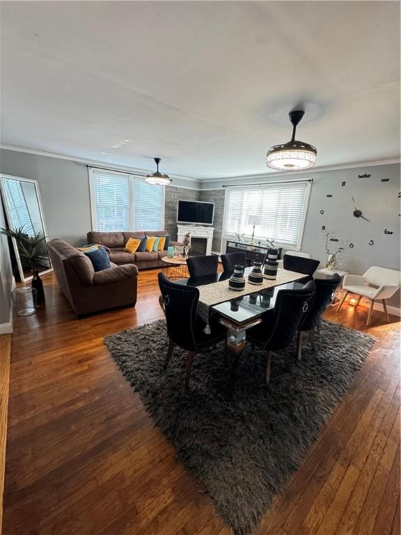 dining room with crown molding, ceiling fan, a fireplace, and hardwood / wood-style floors