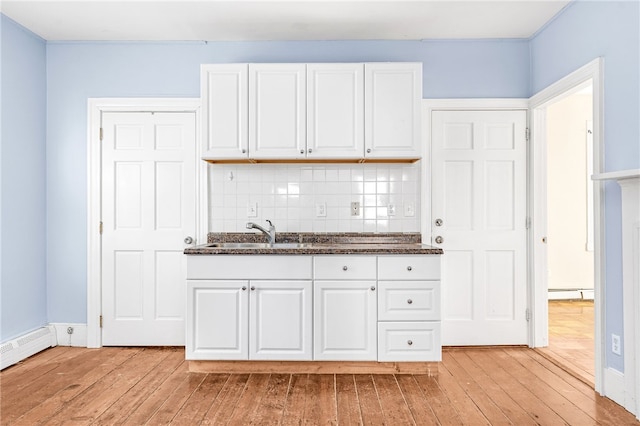 kitchen with sink, a baseboard radiator, light hardwood / wood-style floors, decorative backsplash, and white cabinets