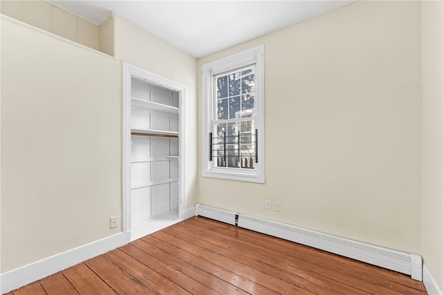 spare room with hardwood / wood-style flooring, plenty of natural light, and baseboard heating