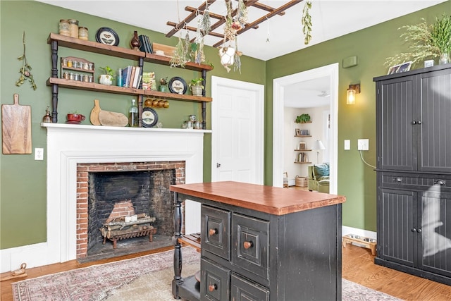 interior space with a kitchen island, a brick fireplace, and light hardwood / wood-style floors