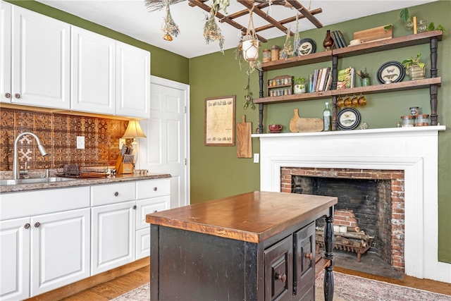 kitchen with sink, tasteful backsplash, light wood-type flooring, a kitchen island, and white cabinets