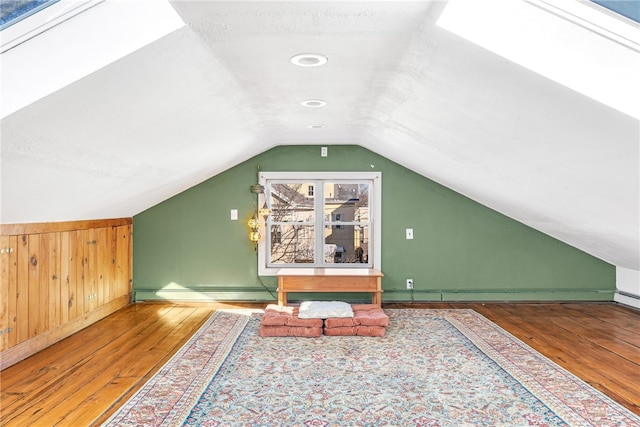 additional living space with a baseboard radiator, lofted ceiling, wood-type flooring, and a textured ceiling