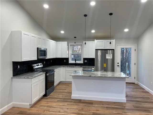 kitchen with hanging light fixtures, white cabinetry, appliances with stainless steel finishes, and a kitchen island