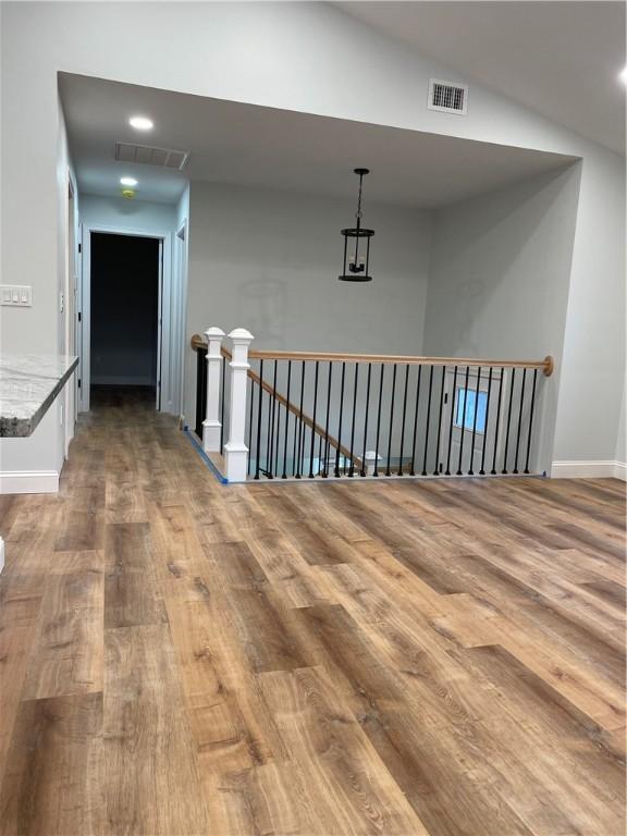 corridor with lofted ceiling and hardwood / wood-style floors