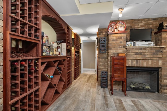 wine area with a fireplace, hardwood / wood-style flooring, and a paneled ceiling