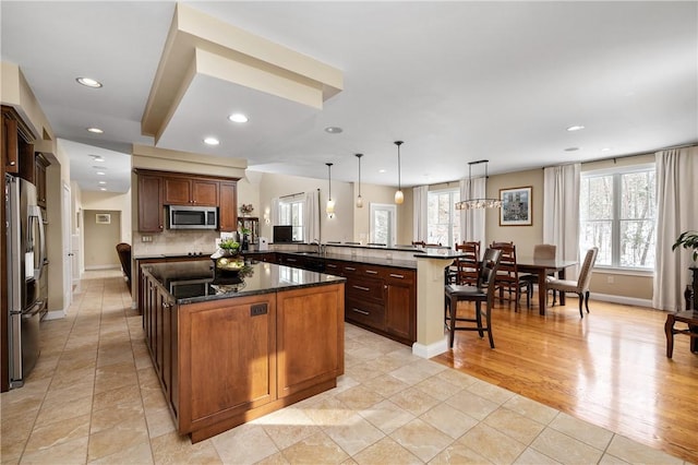 kitchen featuring appliances with stainless steel finishes, a kitchen island, kitchen peninsula, and hanging light fixtures