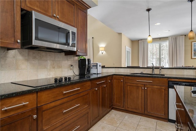 kitchen with appliances with stainless steel finishes, pendant lighting, sink, dark stone countertops, and decorative backsplash