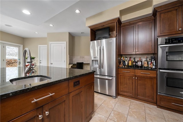 kitchen with sink, backsplash, stainless steel appliances, and dark stone counters