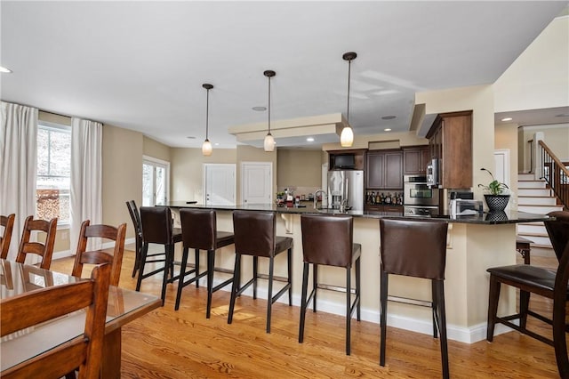 kitchen with pendant lighting, dark brown cabinetry, stainless steel appliances, and a kitchen bar