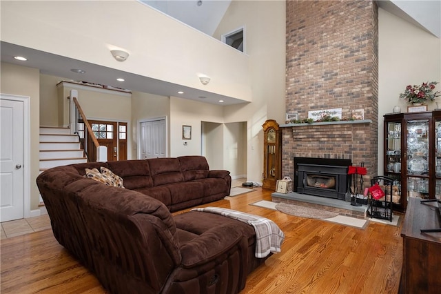 living room with a fireplace, high vaulted ceiling, and light wood-type flooring