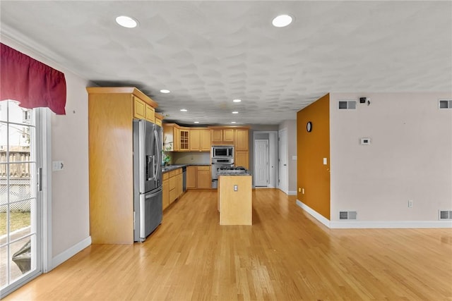 kitchen featuring stainless steel appliances, a kitchen island, and light wood-type flooring