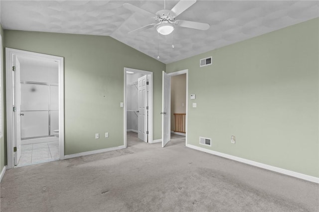 unfurnished bedroom with connected bathroom, a walk in closet, light colored carpet, ceiling fan, and a closet